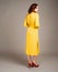 Young ginger woman in yellow shirt dress. Female bright trench at studio background. Inner life concept