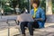 Young girl with afro hair in blue denim shirt sitting on a bench working with her laptop in a park