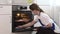 young girl in an apron wipes the oven with microfiber