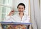 a young girl artist holds a brush in her mouth and carefully examines the picture.