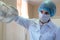 The young girl assistant in a lab coat and protective gloves dentist adjusts the lamp with the light.