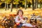 Young girl in autumn park with books and little pumpkin