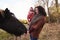 Young Girl On Autumn Walk With Mother Stroking Horse