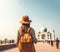 Young girl with backpack in hat stands with her back and looks at Taj Mahal, India. Travel Adventures. Close-up