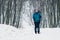 Young girl with backpack hiking uphill through the winter forest