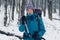 Young girl with backpack points direction with a trekking pole in the winter forest