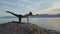 Young girl balances holding yoga pose against seascape