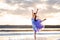 A young girl in a ballet dress stands in the water with clouds reflected.