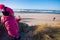 Young girl on beach waving to her mother