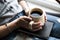 A young girl with a beautiful manicure holds a book with a cup of coffee. Fashion style