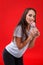 Young girl, bent body and holds a round sweet lollipop near mouth. On a red background.