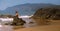 Young girl in bikini and sunglasses sitting on the stones on the beach