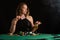 A young girl in a black evening dress plays poker in a casino. on a black background, horizontal photo