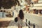 A young girl with black hat in his hand walks along the quay of Rethymno city, Greece. Young girl in a straw hat walking along the