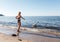 Young girl in a black swimsuit feeds a swan by the sea