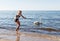 Young girl in a black swimsuit feeds a swan by the sea