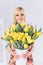 A young girl blonde with a bouquet of yellow tulips in her hands meets spring.