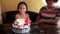 A young girl blows out candles as she celebrates her fifth birthday at home with her family.