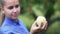 A young girl in a blue shirt looks at an apple