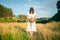 Young girl with bouquet in white dress stands in the middle of the field with his head down. Sadness, loneliness