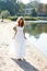 Young girl bride walk barefoot the sunny coast of the river