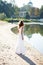 Young girl bride in a white dress on the sunny coast of the river