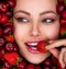 Young girl with bright makeup and a berry background.  Attractive woman tasting cherry and strawberry