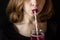 A young girl with bright pink lipstick drinks a cocktail from a glass from a paper tube. The concept of ecology and environmental