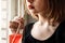 A young girl with bright red lipstick drinks a cocktail from a glass from a paper tube. The concept of ecology and environmental