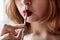 A young girl with bright red lipstick drinks a cocktail from a glass from a paper tube. The concept of ecology and environmental