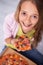 Young girl with a broad smile holding a slice of pizza