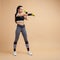 A young girl, a brunette with a ponytail, works out punches using extra weights, a full-length photo.