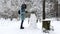 Young girl built funny snowman at winter forest. Happy woman decorating snow man with small fir branches at park