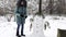 Young girl built funny snowman at winter forest. Happy woman decorating snow man with small fir branches at park