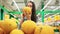 Young girl buys food for a vegan diet. Woman chooses fruit in supermarket. Healthy food, bright yellow vegetables in the