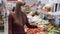 Young girl buys vegetables in grocery department of supermarket and puts them in plastic bag
