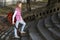 Young Girl Casually Dressed with Guitar in Her Hand Walking Up the Stairs in the Park