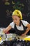 Young girl in a chef`s hat cooks in a large saucepan in a black