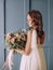 Young girl chic dress bouquet flowers textured wall