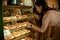 A young girl chooses bakery cakes in the showcases show, represent the variety.