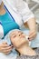 A young girl is cleaning the skin of her face at a cosmetologist. Facial cleansing and massage