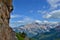 Young girl is climbing on of the routes on Cinque Torri tower. High mountains, blue sky, white clouds.