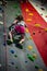 Young girl climbing up on practice wall in indoor rock gym