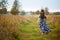 Young girl in a colorful sundress with a wreath on her head goes away along a country road. view from the back