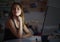 Young girl with computer sitting at desk at night, online dating concept.