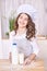 Young girl cooking at kitchen with milk bottle. pretty child portrait. Chef