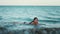 Young girl crawling into sea at beach. Teenager girl relax at sea vacations