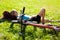 Young girl cyclist enjoying relaxation lying in the fresh green