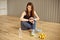 Young girl with dark hair sits on the floor and sets up her fitness tracker to workout in the gym.