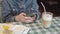 A young girl in a denim jacket prints a text message on her smartphone sitting in a restaurant.